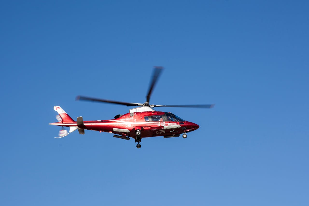 heros-img Red helicopter flying against clear blue sky, symbolizing emergency medical rescue.